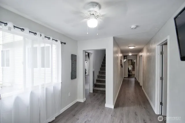a view of a hallway with wooden floor and a bathroom