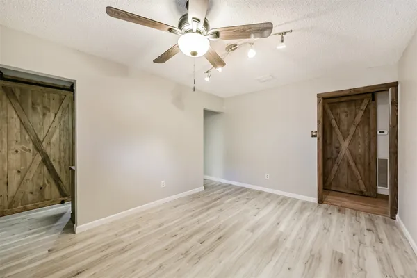 an empty room with wooden floor fan and windows
