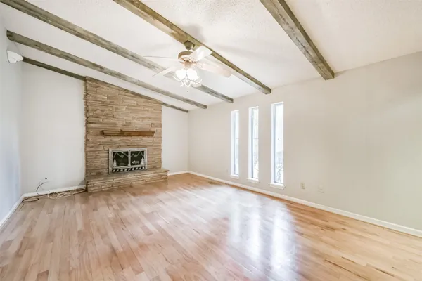 a view of an empty room with wooden floor fireplace and a window