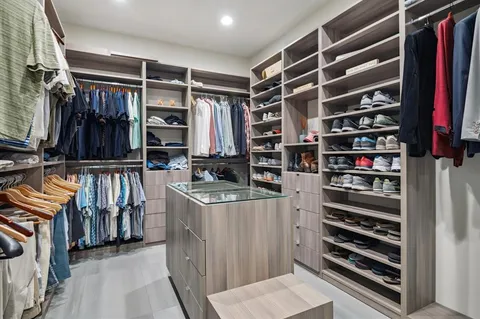 a view of walk in closet with clothes and shoes