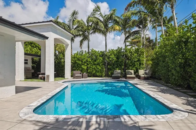 a view of a swimming pool with a yard and palm trees