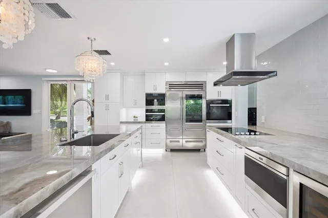 a large kitchen with granite countertop a large kitchen island a sink stainless steel appliances and cabinets