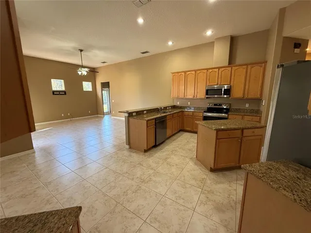 a large kitchen with kitchen island granite countertop wooden cabinets a granite counter tops and a stove