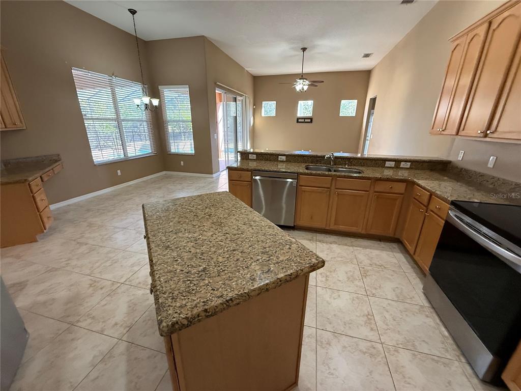 3231 Pawleys Loop North St. Cloud, FL 34769 - Photo 8 of 34 a large kitchen with kitchen island granite countertop wooden cabinets a granite counter tops and a stove