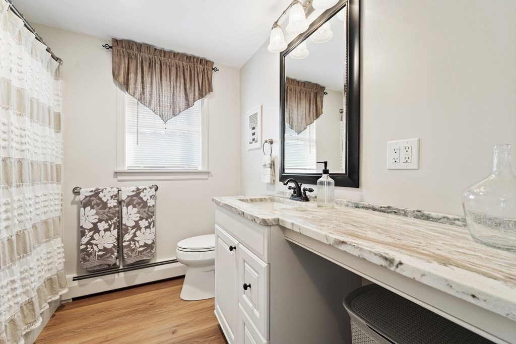 26-28 South Road Londonderry, NH 03053 - Photo 19 of 27 a bathroom with a granite countertop sink a toilet and a mirror