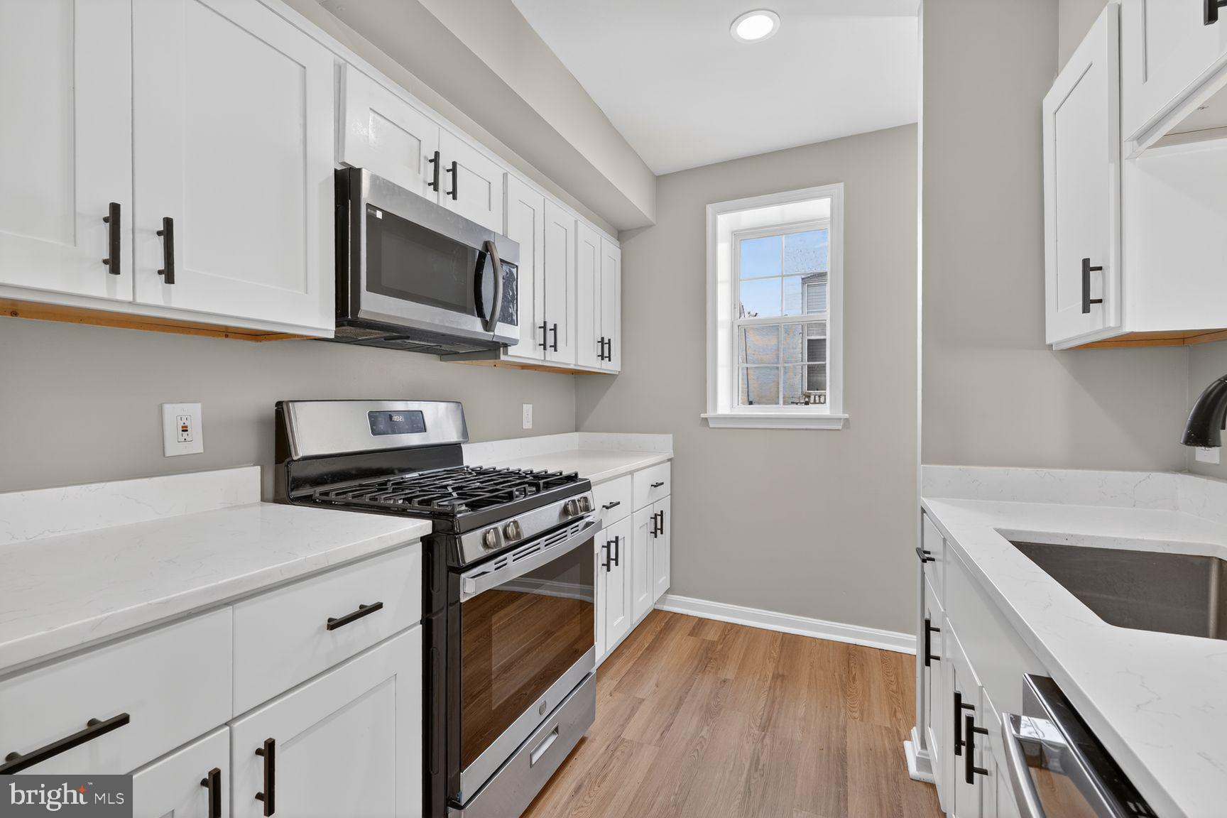 1008 Rittenhouse Street Northwest, Unit 15 Washington, DC 20011 - Photo 13 of 39 a kitchen with stainless steel appliances granite countertop a stove a sink and a microwave