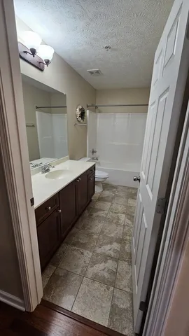 a spacious bathroom with a double vanity sink a toilet and a mirror