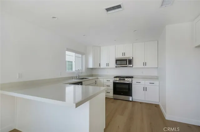 a kitchen with granite countertop white cabinets and stainless steel appliances
