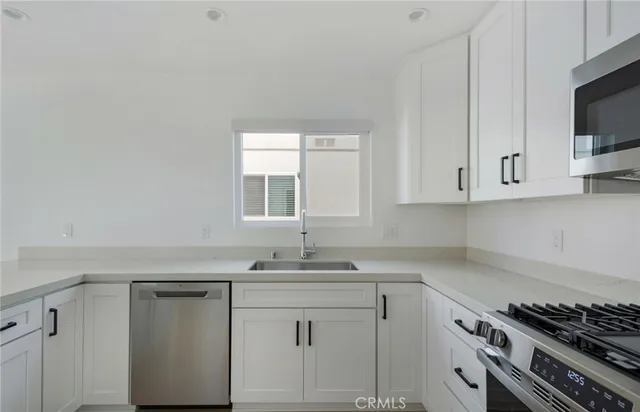 a kitchen with white cabinets sink and stove