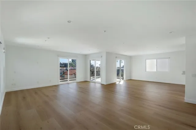 a view of an empty room with wooden floor and window