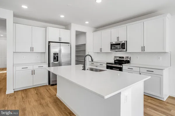 a kitchen with stainless steel appliances a refrigerator sink and white cabinets