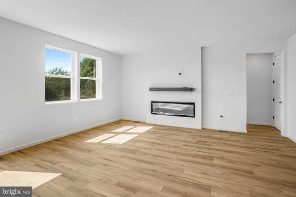 a view of an empty room with a window and a kitchen