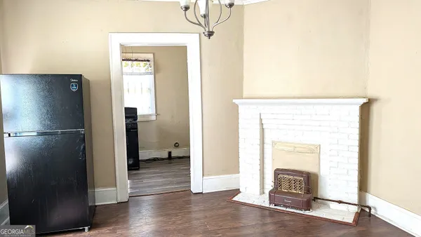 a view of empty room with wooden floor and kitchen