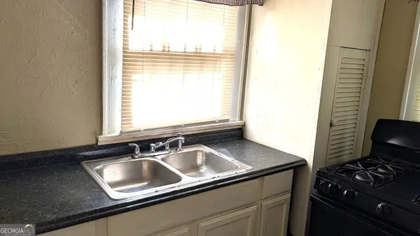 a kitchen with a sink a counter cabinets and a window