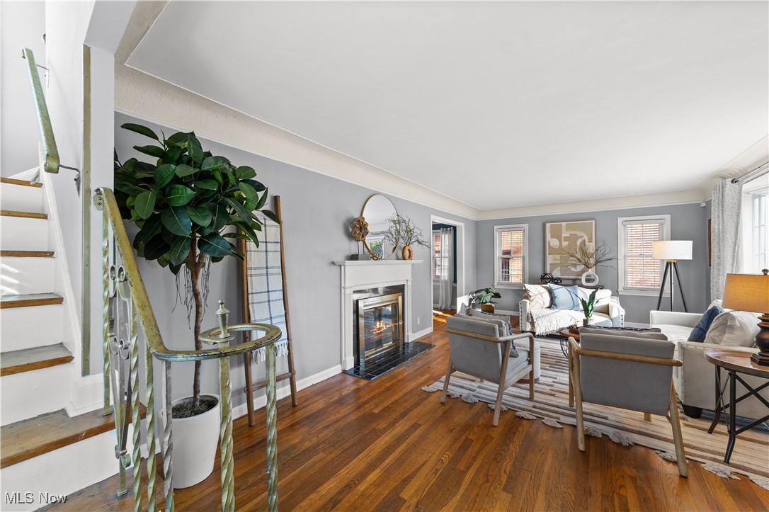 Living room with stairs, dark wood-type flooring, and a fireplace with flush hearth