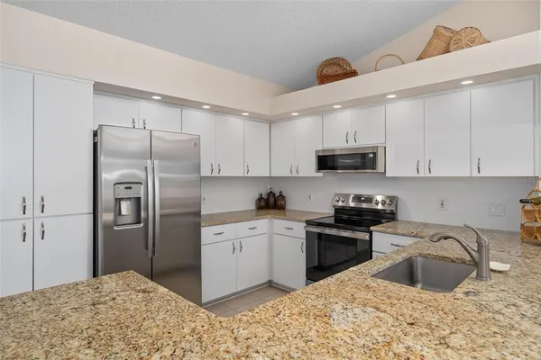 a kitchen with stainless steel appliances granite countertop a sink stove and refrigerator