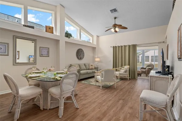 a dining room with wooden floor a chandelier a glass table and chairs
