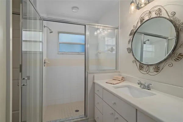 a bathroom with a granite countertop sink mirror vanity and shower