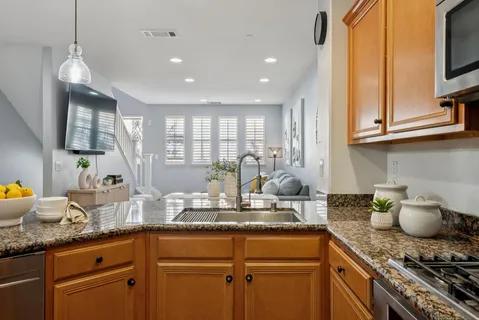 a kitchen with stainless steel appliances granite countertop a sink a stove a dining table and chairs
