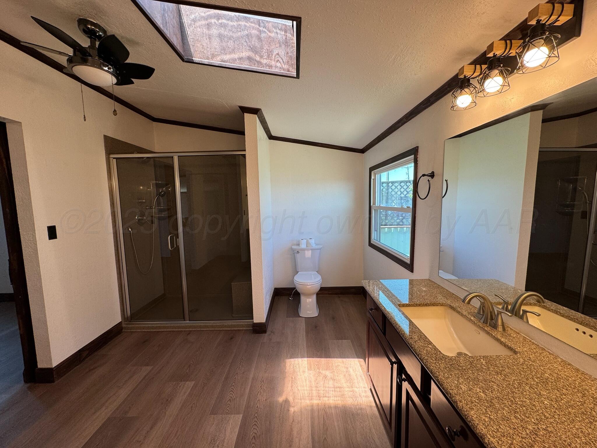 403 Aaron Road Fritch, TX 79036 - Photo 8 of 31 a bathroom with a granite countertop sink a toilet a mirror and shower