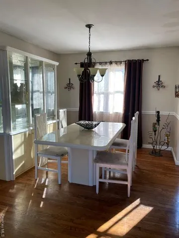 a dining room with wooden floor a chandelier a wooden table and chairs