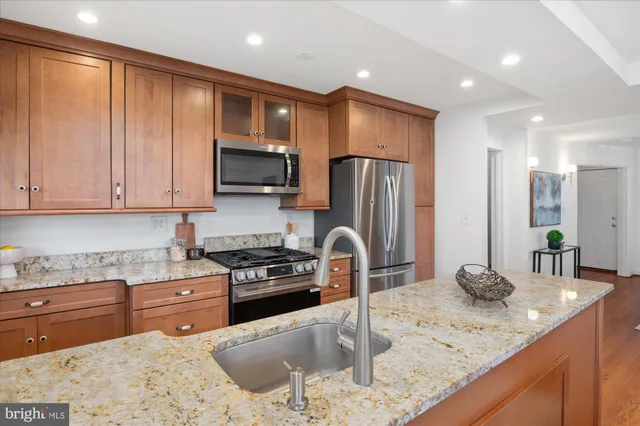 a kitchen with stainless steel appliances granite countertop a sink refrigerator and cabinets