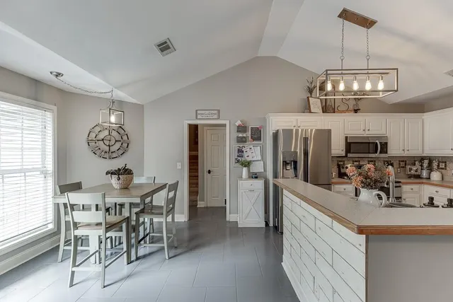 a view of a dining room and livingroom with furniture wooden floor a chandelier