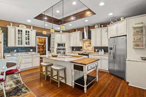a kitchen with stainless steel appliances a stove a sink dishwasher a refrigerator and cabinets with wooden floor