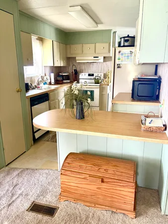 a room with stainless steel appliances kitchen island granite countertop furniture and a view of living room