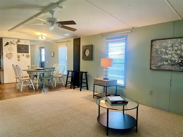 a dining hall with stainless steel appliances kitchen island granite countertop a table chairs and a sink
