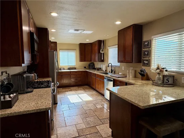 a kitchen with stainless steel appliances granite countertop a sink counter space cabinets and a large window