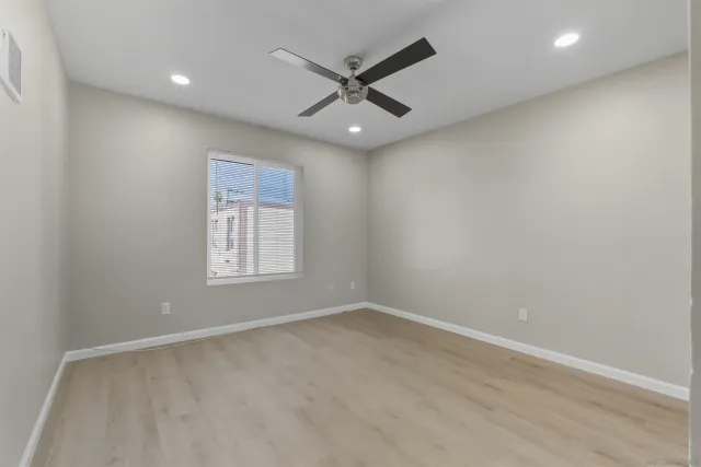 an empty room with a window and a ceiling fan