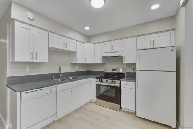 a kitchen with white cabinets sink and white stainless steel appliances