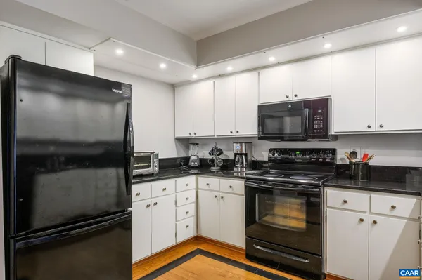 a kitchen with granite countertop a stove a sink and white cabinets