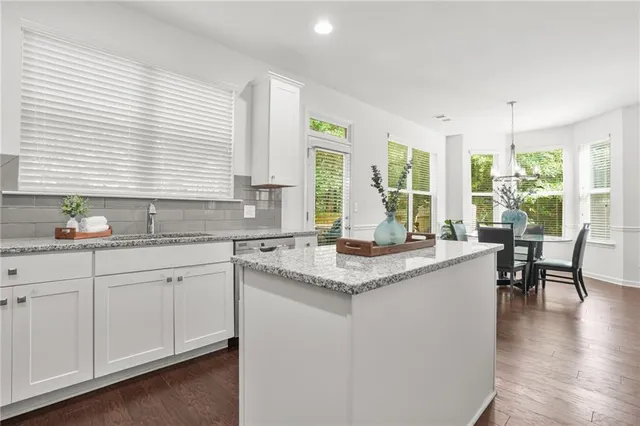 a kitchen with granite countertop sink window and cabinets