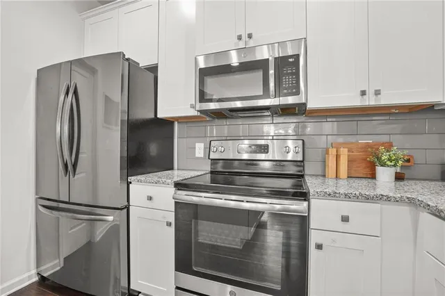 a kitchen with granite countertop stainless steel appliances and white cabinets