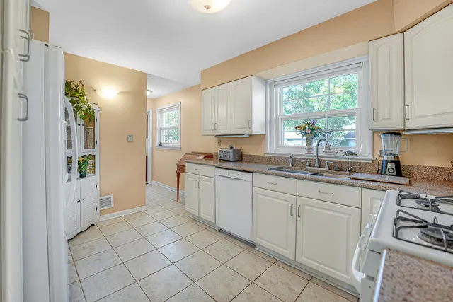 a kitchen with white cabinets and a window