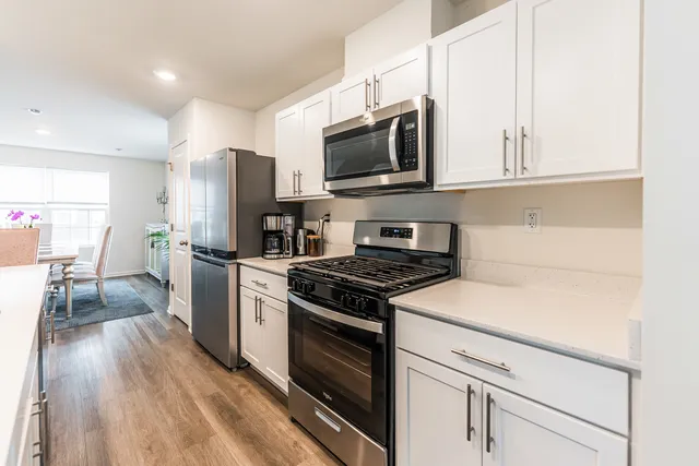 a kitchen with stainless steel appliances white cabinets and wooden floor