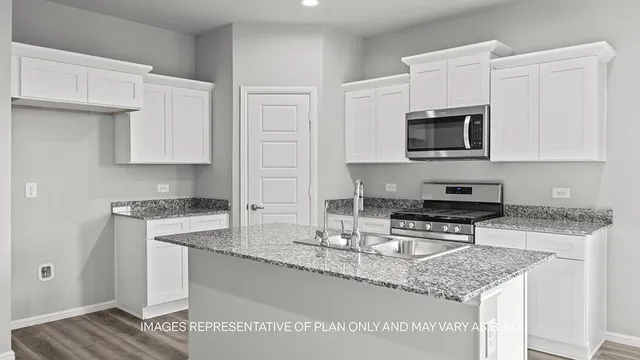 a kitchen with granite countertop a stove sink and microwave