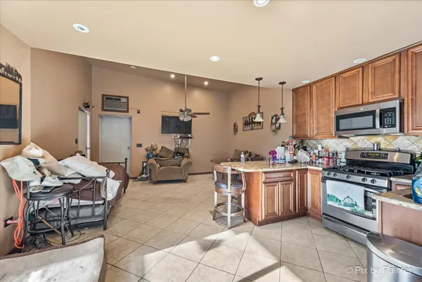 a kitchen with stainless steel appliances kitchen island granite countertop a stove a sink a dining table and chairs
