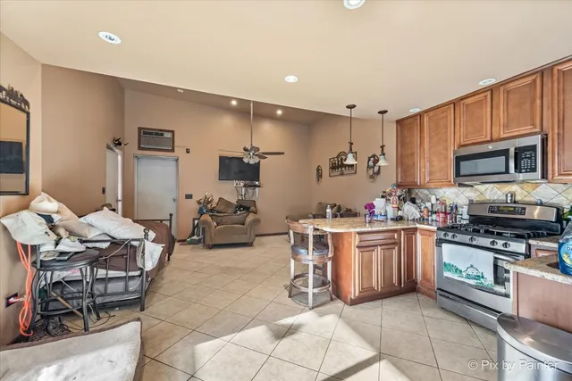 a kitchen with stainless steel appliances kitchen island granite countertop a stove a sink a dining table and chairs