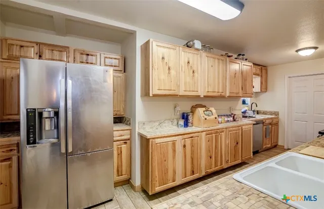 a kitchen with stainless steel appliances granite countertop a refrigerator a stove and a sink with wooden floor