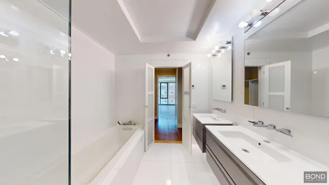 a spacious bathroom with a bathtub double vanity sink and a mirror