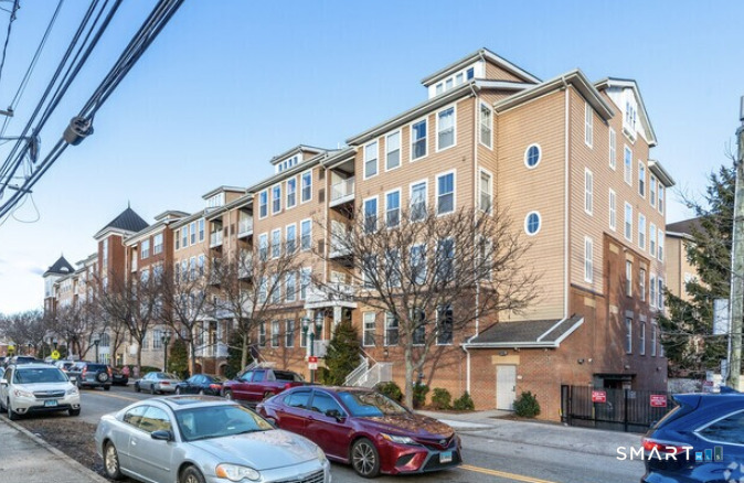 25 Adams Avenue, Unit 112 Stamford, CT 06902 - Photo 2 of 17 a front view of a building with lot of cars and trees