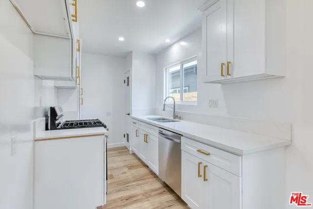 a kitchen with white cabinets and sink