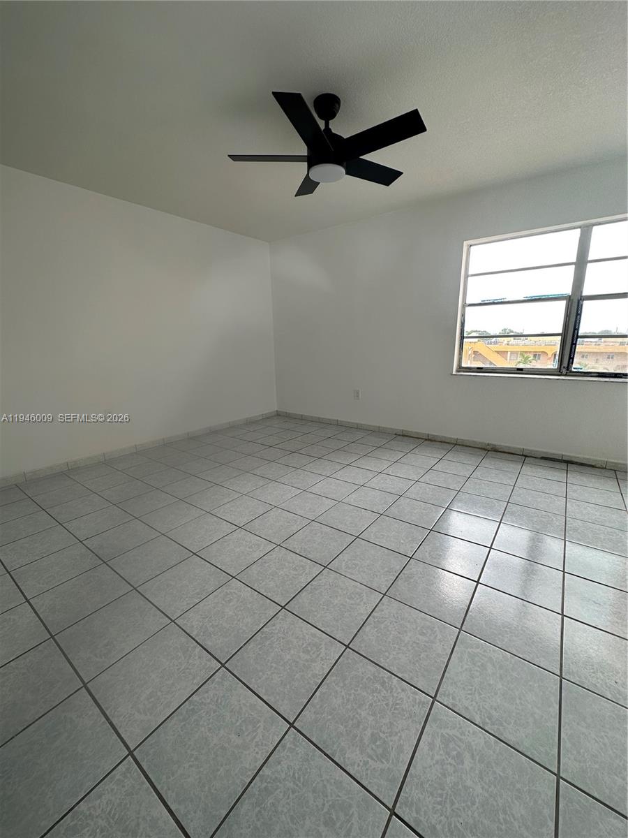 4670 West 13th Lane, Unit 405 Hialeah, FL 33012 - Photo 7 of 16 an empty room with windows and ceiling fan