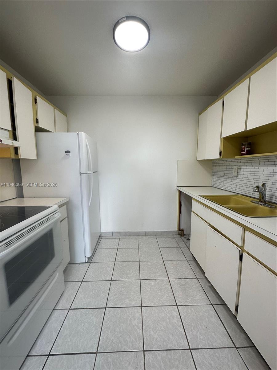 4670 West 13th Lane, Unit 405 Hialeah, FL 33012 - Photo 10 of 16 a kitchen with a stove a sink and a refrigerator