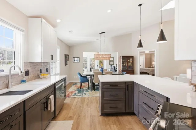 a kitchen with stainless steel appliances granite countertop a sink a stove and a wooden floors
