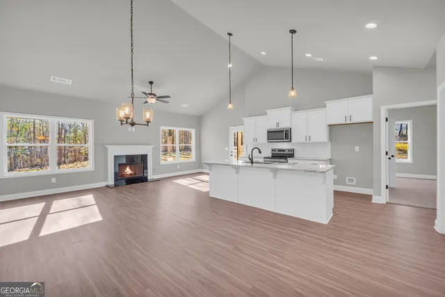 a view of an empty room with wooden floor fireplace and a window