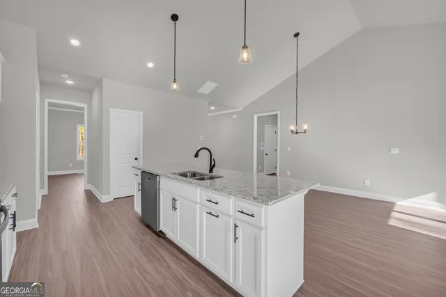 a kitchen with stainless steel appliances granite countertop a stove a sink and white cabinets with wooden floors